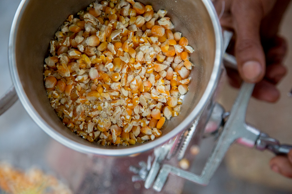 A group member uses a milling machine to prepare the maize for eating
